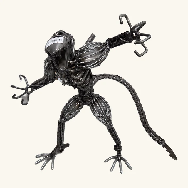 Alien IV metal sculpture with its original head label, outstretched claws, ribbed body, complete feet and long arched chain tail.