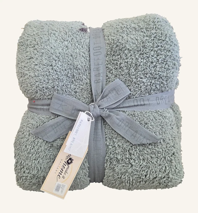 Agave Green Multi CozyChic Navarro throw by Barefoot Dreams, folded with its original gray ribbon and attached tags.