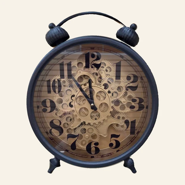 Black twin-bell-style table clock with large Arabic numerals, brass-tone gears, dark hands, curved top handle, and two feet.