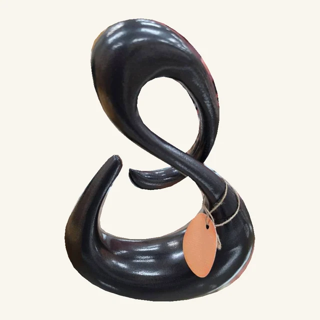 Glossy black looping knot sculpture with its complete curved base, original orange hang tag and tied cord