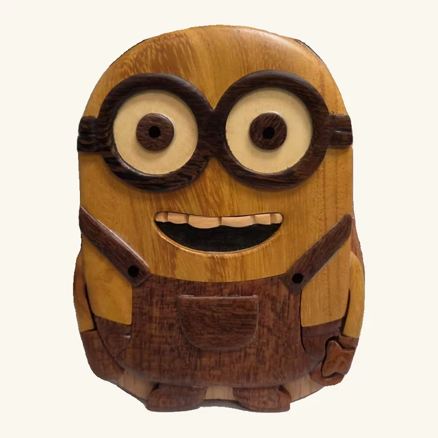 Bob Minion wooden puzzle box with round layered goggles, a smiling face, contrasting wooden overalls, carved hands and two feet.
