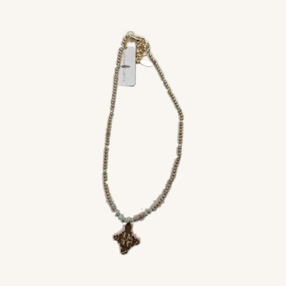 Caitlin beaded necklace with its actual cross pendant, pale beads, oval charm and attached tag