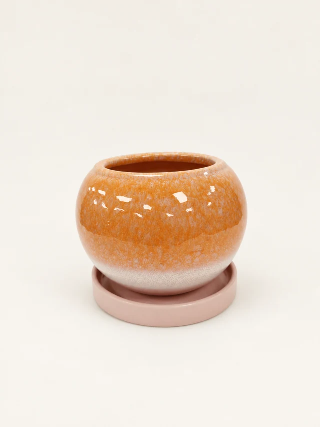 Rounded orange-and-cream glazed Casey pot with a pale-pink saucer