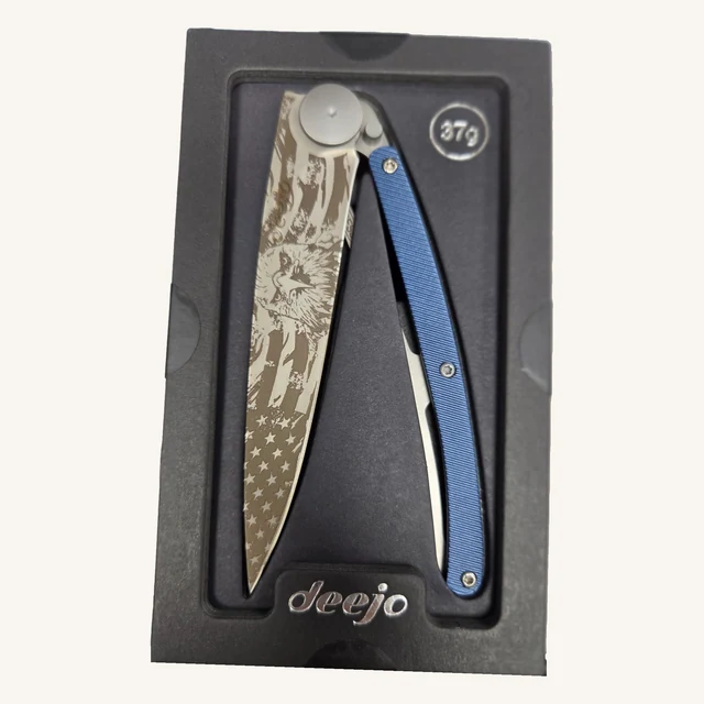 Deejo American Bald Eagle 37g folding knife with eagle-and-flag engraving and textured blue aluminum handle in its black presentation tray