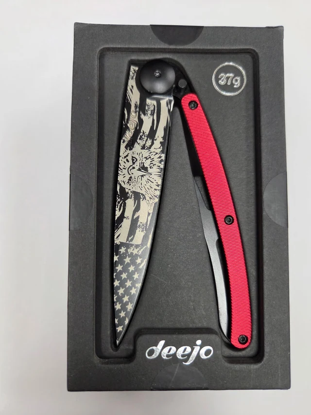 Complete Deejo American Bald Eagle folding knife with eagle-and-flag blade artwork and textured red aluminum handle in its black presentation tray