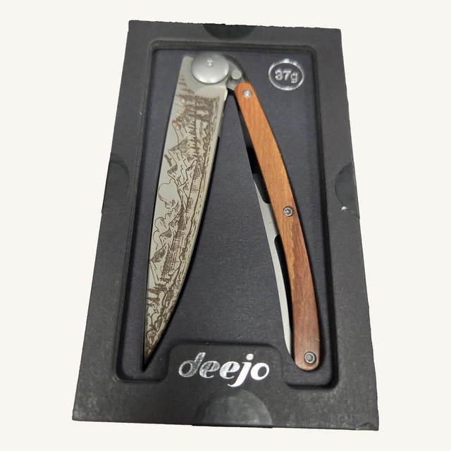 Deejo Mountain 37g folding knife with mountain-landscape engraving and coral-wood handle in its black presentation tray