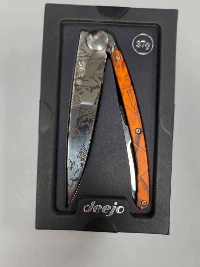 Complete Deejo On the Lookout folding knife with wildlife blade artwork and an orange-camouflage handle in its black presentation tray