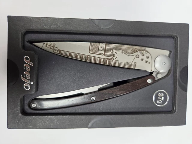 Complete Deejo Rock'n Roll folding knife with electric-guitar and amplifier blade artwork and an ebony-wood handle in its black presentation tray