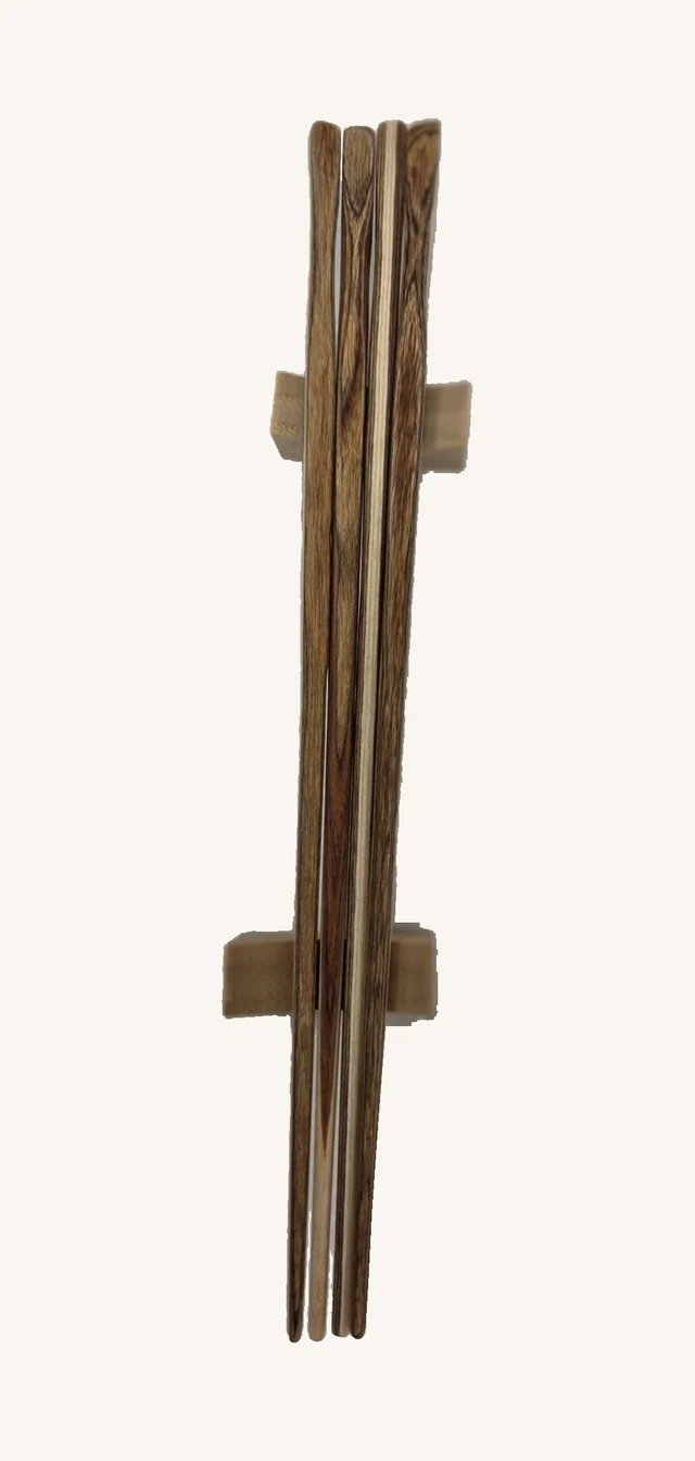 Four Drift wooden chopsticks with two rests in their original overlapping arrangement, showing brown, tan and cream grain