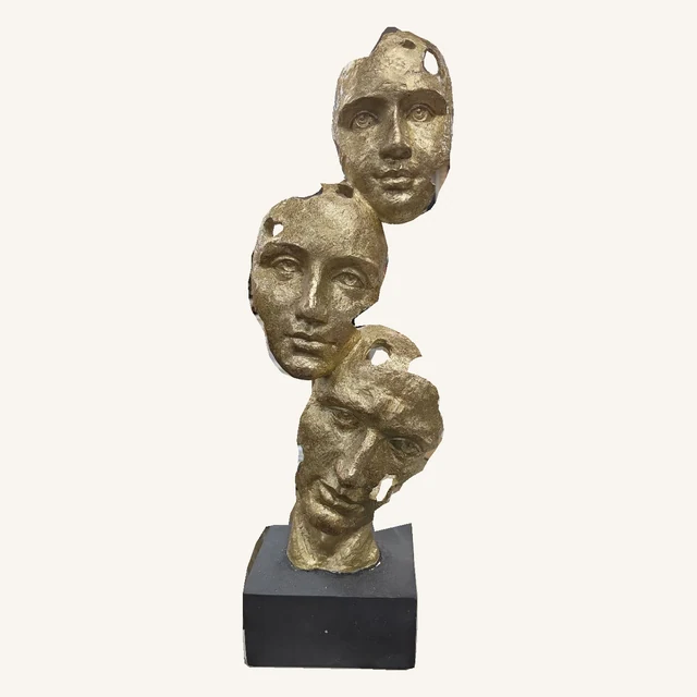 Front of the complete textured gold three-face sculpture with its original cutouts and dark square base