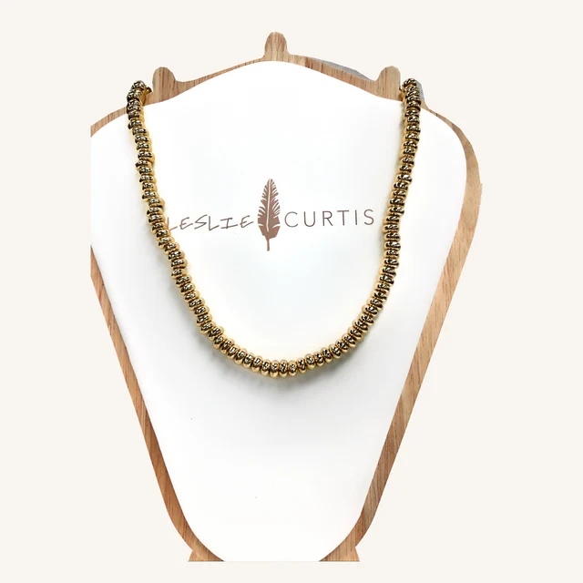 Kassidy necklace with a strand of glossy flattened gold-tone beads on its original Leslie Curtis display