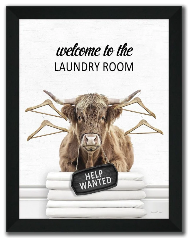 Complete black-framed Laundry Room Highland artwork with a Highland cow, four coat hangers, folded white linens and a Help Wanted sign