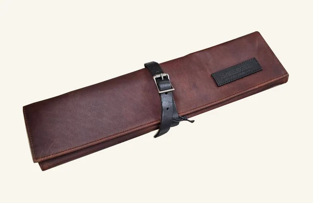 Cognac-brown Hardmill compact leather knife roll, closed, with original black strap, buckle, stitching, tie and embossed brand patch