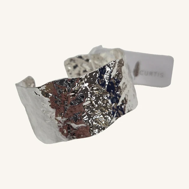 Lena Hammered Cuff Bracelet — Silver Tone. A broad hammered surface gives this adjustable silver-toned cuff its textured shine.