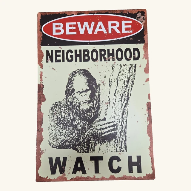 Complete decorative BEWARE NEIGHBORHOOD WATCH tin sign showing Bigfoot peering around a tree, with original printed artwork, distressed border and rounded corners