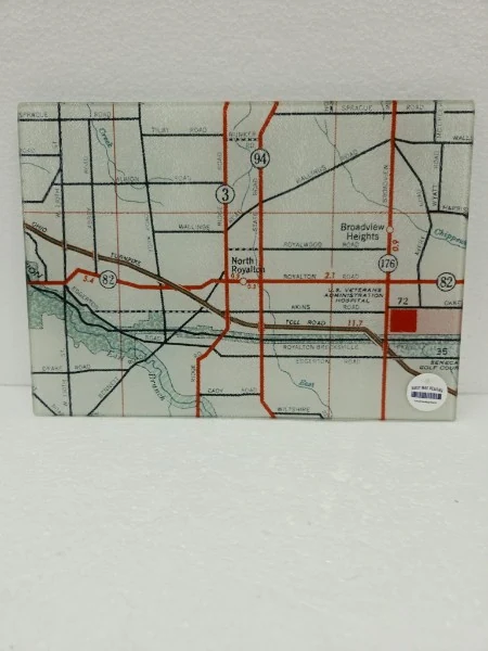 Complete North Royalton map small glass cutting board with red roads, local map details and its original round product sticker on a plain white background