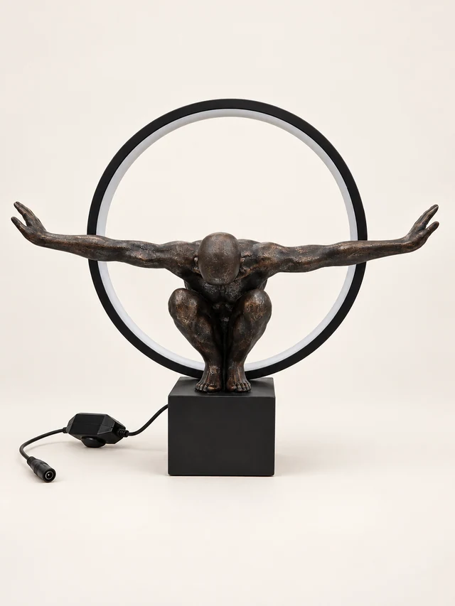Crouching dark bronze-tone figure table lamp with circular ring, black base and pictured cord and adapter