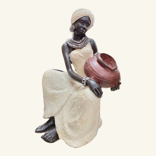 Seated woman sculpture in a textured cream dress and headwrap holding a rounded reddish-brown pot