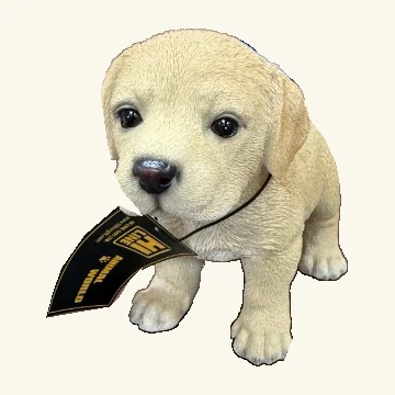 Standing pale yellow Labrador puppy figurine with floppy ears, dark eyes, a black nose and its original hang tag and cord.